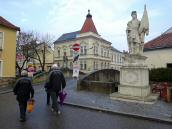 Wanderer bei der Loisbachbrcke mit der Figur Hl. Urban im Vordergrund der Figurenbildstock Hl Florian